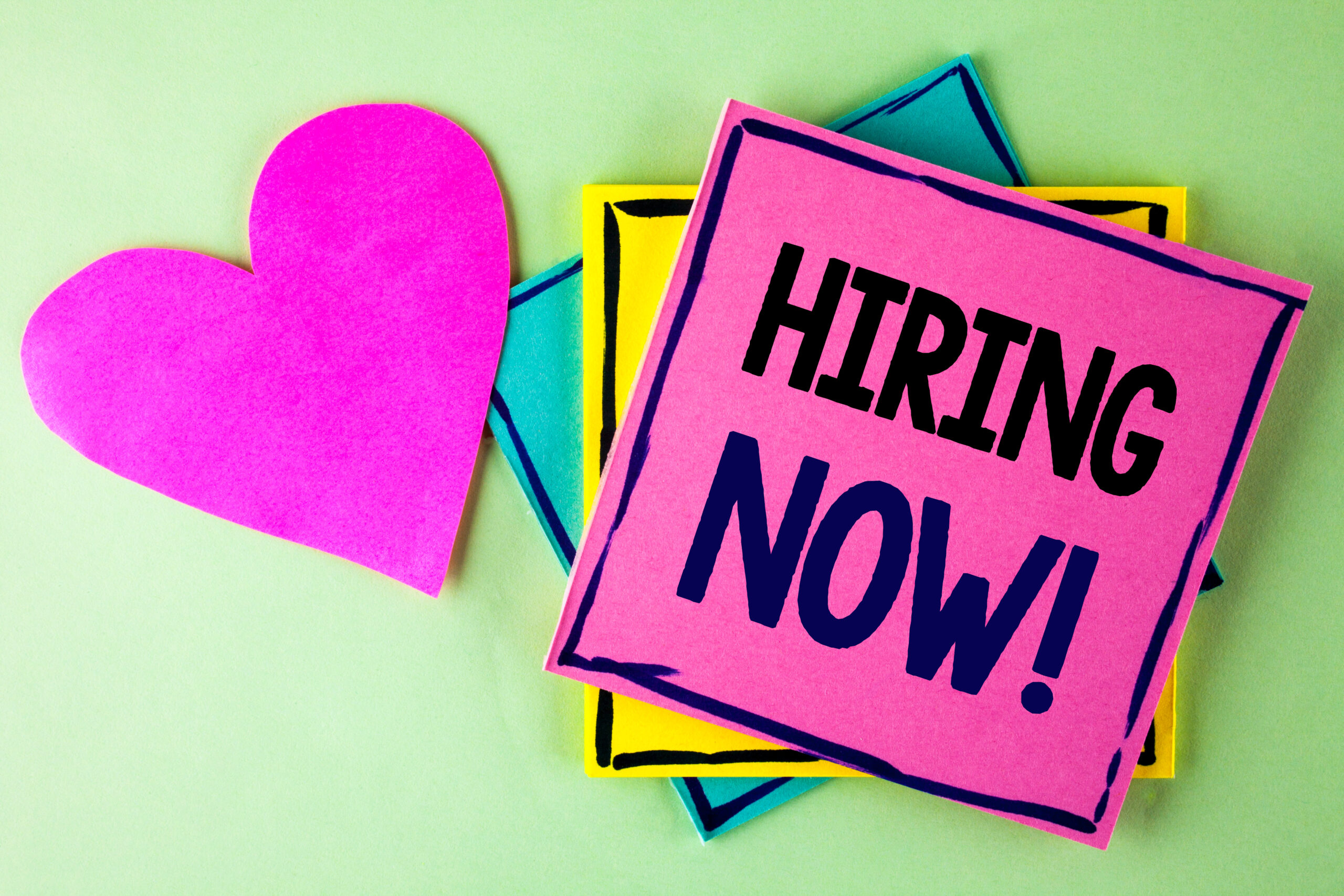 Writing note showing Hiring Now Motivational Call. Business photo showcasing Workforce Wanted New Employees Recruitment written on Pink Sticky Note Paper on plain background Heart next to it.